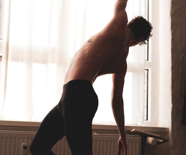 Man stretching by a window with morning light.